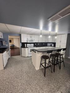 a large kitchen with white cabinets and bar stools at House in Hannibal in Hannibal