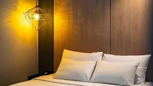 a bed with white pillows and a light above it at Hotel Deluxe in Tumo