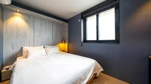 a bedroom with a large white bed with a window at Hotel Deluxe in Tumo