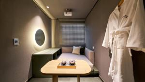 a small room with a bed and a table at Anook Hotel Busan Gwangalli in Busan