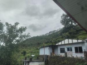 a white building with a hill in the background at Inaya resort in Phata