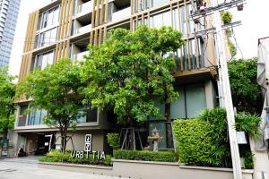 a building with a tree in front of it at Urbitia Thonglor in Klong Toi