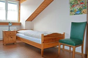 a bedroom with a bed and a green chair at Ferienwohnung Wiedenhofer in Regenstauf