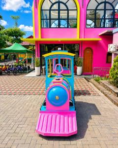 a toy train sitting in front of a pink building at Onsen Resort Kaliurang in Mantaak