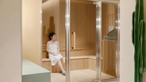 a woman in a white dress sitting in a glass elevator at Anook Hotel Busan Gwangalli in Busan