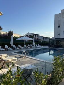 a swimming pool with chairs and umbrellas next to a building at Aurum Apartmanı in Vodice