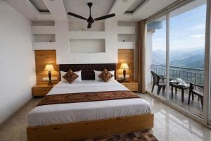 a bedroom with a large bed and a balcony at Hotel The Nature Heaven, Mussoorie - Affordable Luxury Stay in Mussoorie with Mountain View in Mussoorie
