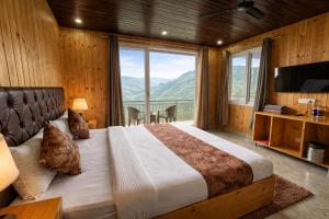 a bedroom with a large bed with a large window at Hotel The Nature Heaven, Mussoorie - Affordable Luxury Stay in Mussoorie with Mountain View in Mussoorie