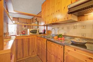 a kitchen with wooden cabinets and a bowl of fruit on the counter at Appartamento Bareu Mountain View - Happy Rentals in Sauze dʼOulx