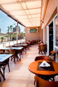 an empty restaurant with tables and chairs and windows at Comfort Hotel Sertãozinho in Sertãozinho