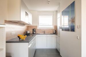 a kitchen with white cabinets and a bowl of fruit on a counter at Ferienwohnung Badespaß am Schlosssee Salem in Salem