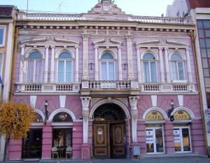 a pink building on a street in a city at Bookworm Ultracentral Cozy, ultracentral apartment for people who appreciate comfort, details and books in Târgu-Mureş