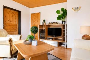 a living room with a tv and a table at Dünenlounge Dornumersiel in Dornum