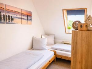 two beds in a small room with a window at Dünenlounge Dornumersiel in Dornum