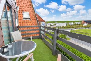 a balcony with a table and chairs and a fence at Seehund in Neuharlingersiel +44 photos
