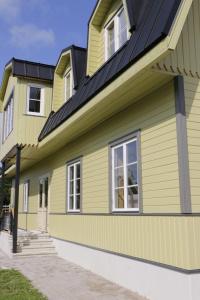 a yellow house with a black roof at Kärdla Retrovisiit Kirsi, Tiina ja Linda in Kärdla
