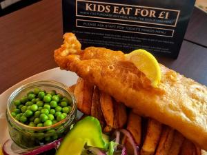 a plate of food with fish and chips and peas at Miners Lamp Apartment in Easington