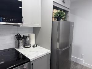 a kitchen with a stainless steel refrigerator and white cabinets at A very cozy 2-bedroom apartment in Calgary +19 photos