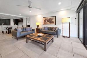 a living room with two couches and a table at Poolside Bliss: A Modern Resort Sanctuary in Port Douglas