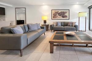 a living room with a couch and a coffee table at Poolside Bliss: A Modern Resort Sanctuary in Port Douglas +10 photos