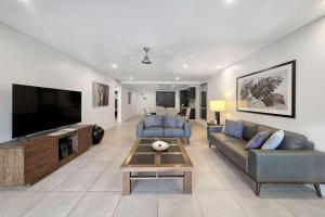 a living room with a couch and a tv at Poolside Bliss: A Modern Resort Sanctuary in Port Douglas