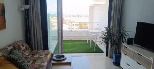 a living room with a sliding glass door with a table at Playa del ingles Tamaran apartamento 509 in Maspalomas