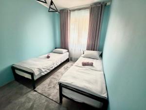 two twin beds in a room with a window at Joy Fergana Guesthouse in Fergana +1 photo