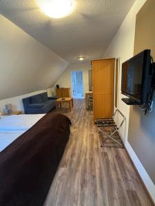 a bedroom with a bed and a flat screen tv at ManusFaktur Waldcafé und Hotel in Nordhastedt