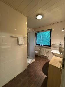 a bathroom with a sink and a toilet and a window at ManusFaktur Waldcafé und Hotel in Nordhastedt