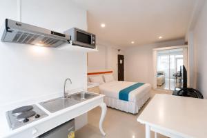 a hotel room with a bed and a kitchen with a sink at Suk41 Bangkok Hotel in Bangkok