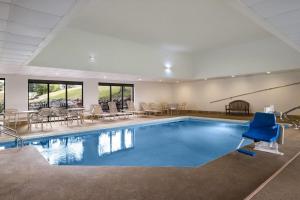 a pool with blue chairs and tables in a building at AmericInn by Wyndham Madison West in Madison