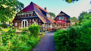 a large house with a large roof and a patio at Ihr Ferien Hotel Brunnenhof in Suhlendorf