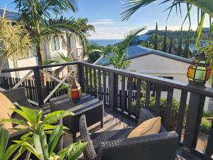 a balcony with chairs and a table and the ocean at Darlene's Nest in Cable Bay