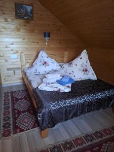 a bed in a wooden room with pillows on it at Cabanutele Geo in Lacu Rosu