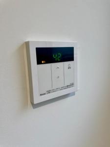 a digital clock on a wall with a clock on it at サニーサイドホステル2号館 in Uji