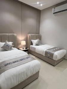 a bedroom with two beds and a lamp at فندق فاليا in Al Kharj