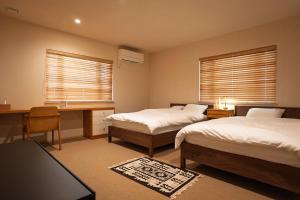 a bedroom with two beds and a desk and two windows at u10 -ユーテン- in Kakegawa