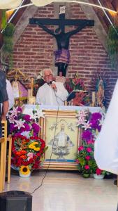 a pope speaking into a microphone in front of a cross at Cabañas Recor in Tepoxcuautla