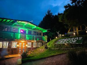 a house with a green lighted sign in front of it at Cabañas Recor in Tepoxcuautla