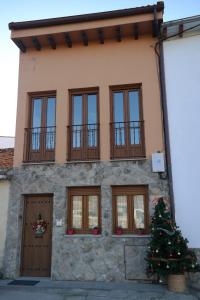 una casa con un árbol de Navidad delante de ella en Apartamentos Valle&Snow, en Vallejera de Riofrío