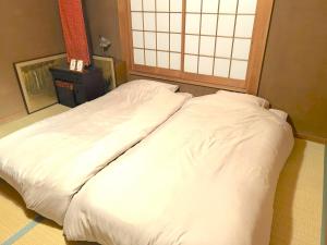 a large white bed in a room with a window at Jokan-en in Honjo
