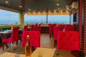 a restaurant with red chairs and a bottle of wine at Hotel La Casa, Amritsar #swimming pool #prime location #luxury rooms #best selling hotel near golden temple in Amritsar