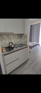 a kitchen with white cabinets and a sink and a bed at Alvina complex in Tsaghkadzor