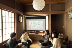 a group of people sitting in a room playing a video game at Jokan-en in Honjo