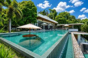 an infinity pool with an umbrella next to a house at Villa Skyfall Thailand Phuket in Panwa Beach