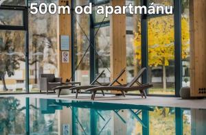 a room with chairs and a pool in front of a building at 365 apartmány AUPARK in Piešťany