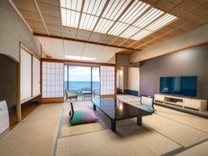 a living room with a table and a television at Dogashima New Ginsui in Nishiizu