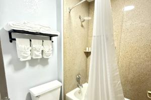 a bathroom with a shower and a toilet and towels at Baymont by Wyndham Tallahassee in Tallahassee