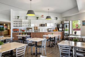 a restaurant with tables and chairs and a kitchen at Super 8 by Wyndham Winnipeg West in Saint James