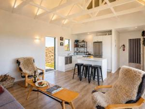 a living room with a table and chairs and a kitchen at Overview - Stay Waiheke in Ostend
